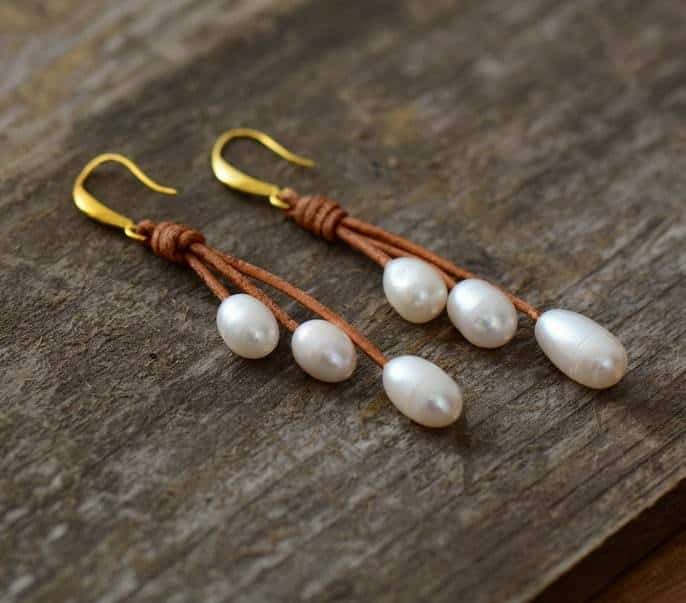 paire de boucles d'oreilles à fermoir doré avec trois perles blanches nacrées en superposition avec fil marron