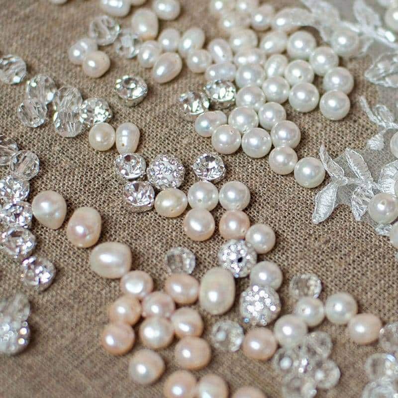 perles blanches nacrées avec des petits diamants posé sur un fond beige