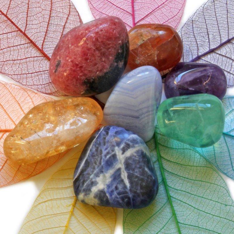 7 pierres de toutes les couleurs entourées de feuilles de toutes les couleurs