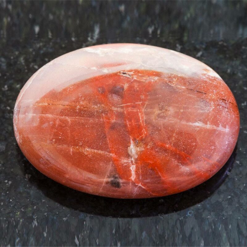 grosse pierre de jaspe ronde plate rouge sur fond marbré noir