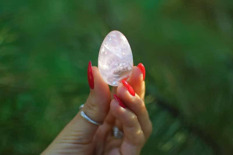 Oeuf de yoni en quartz rose tenu dans une main