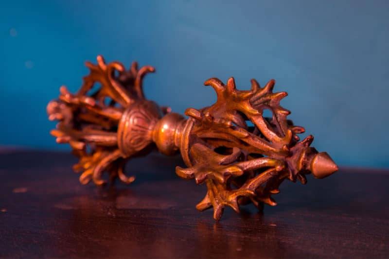 Dorje vajra sur une table en bois sur fond bleu.