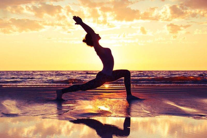 Jeune femme sur la plage pratiquant le yoga