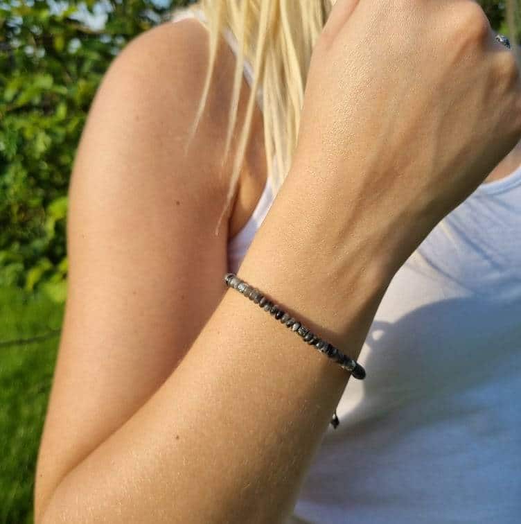 femme blonde portant au poignet un fin bracelet avec des petites pierres en forme de billes grise