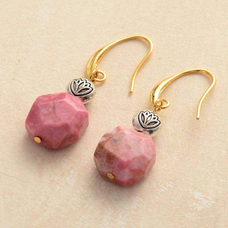 paire de boucles d'oreilles avec pierre ronde rose et pendentif argent fleur de lotus avec fermoir or sur fond beige