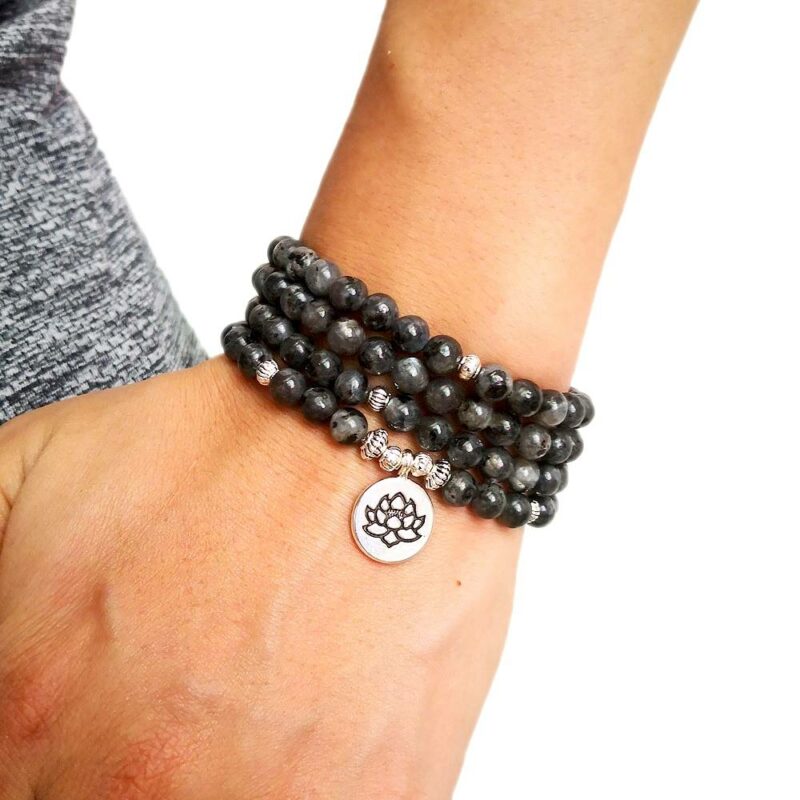 bracelet collier type chapelet en billes de pierre couleur noir avec médaillon rond lotus enroulé autour d'un poignet
