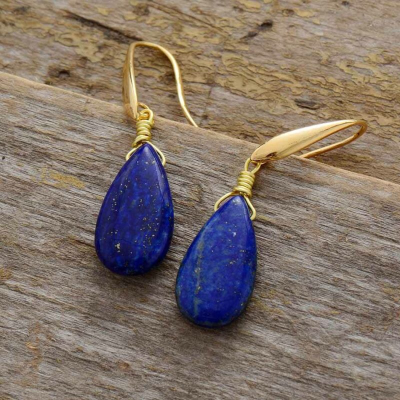 paire de boucles d'oreilles en forme de goutte d'eau en pierre lapis lazuli bleue avec fermoir doré sur du bois