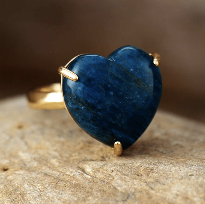 fine bague en or avec une pierre en forme de coeur bleu nuit posé sur une table