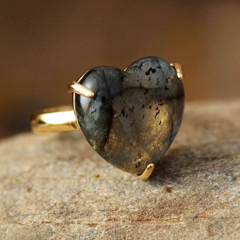 fine bague en or avec une pierre en forme de coeur bleu noir posée sur une table