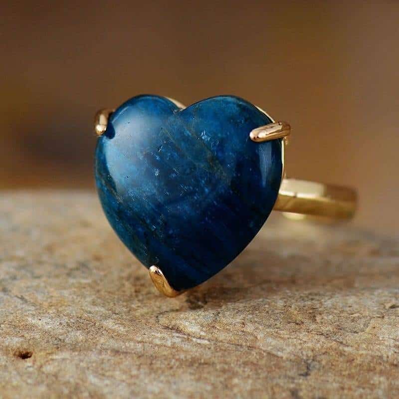 fine bague en or avec une pierre en forme de coeur bleu nuit posé sur une table