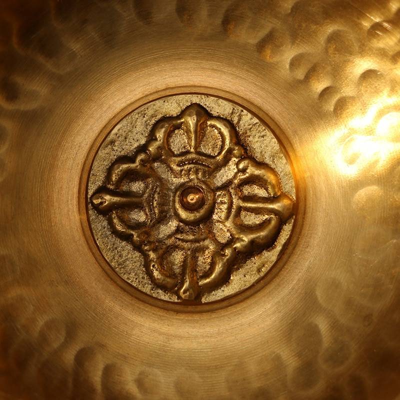 fond d'un bol tibétain en métal doré avec un motif gravé et en relief
