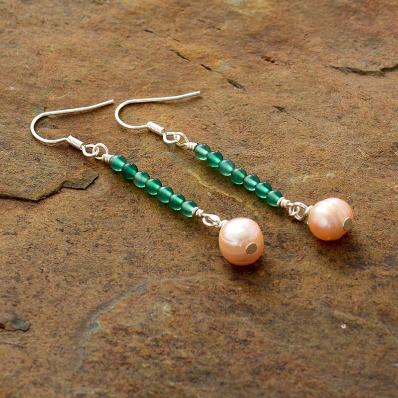 paire de boucles d'oreilles perles vertes transparentes alignées le long d'un fil avec une plus grosse pierre rose au bout et fermoir argent