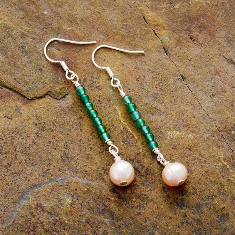 paire de boucles d'oreilles perles vertes transparentes alignées le long d'un fil avec une plus grosse pierre rose au bout et fermoir argent