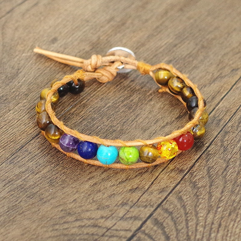 Bracelet septs chakras en cuir et oeil de tigre sur fond marron en bois