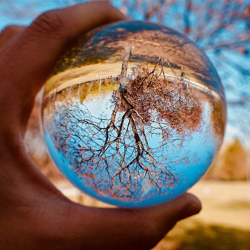 Boule de cristal tenue par une main devant un paysage d'autaumne