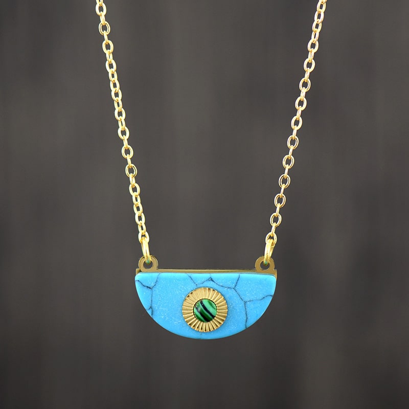 Collier à maillons plaqués or avec pendentif de demi-lune en turquoise et malachite sur fond gris foncé