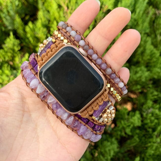 Bracelet pour montre Apple en améthyste dans une main sur fond d'herbe