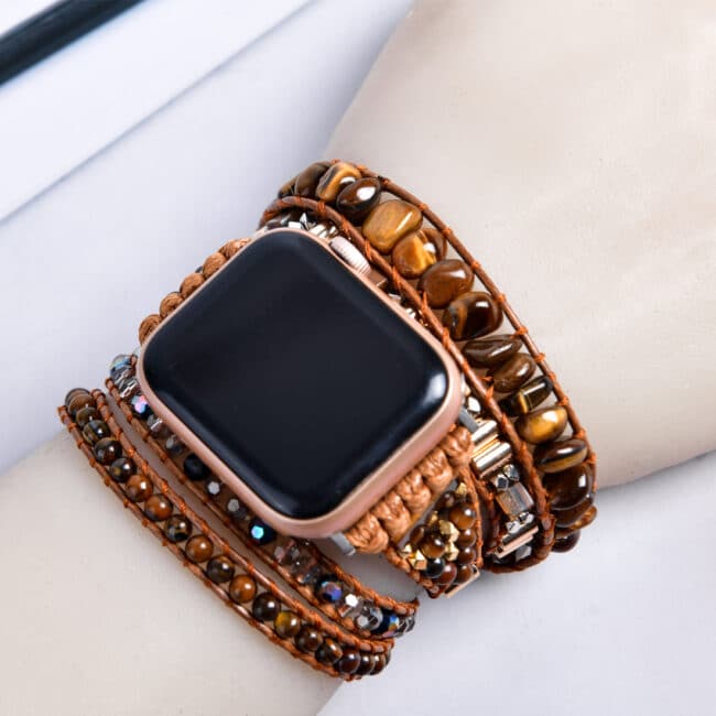 Bracelet ethnique pour Apple watch en pierre d'oeil de tigre porté sur un poignet sur fond blanc