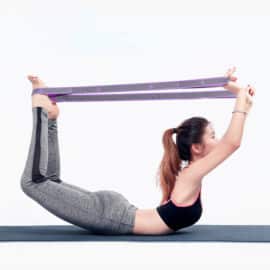 Ceinture de résistance pour yoga utilisée par une femme allongée sur le ventre sur fond gris