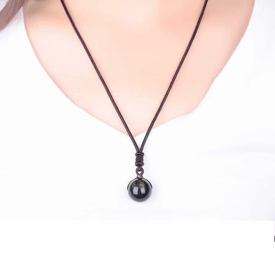 Collier Pierre Naturelle avec Pendentif en Perle d'Obsidienne Dorée sur une personne avec un t-shirt blanc