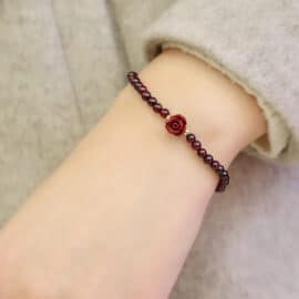 Bracelet Tibétain Fin en Perles de Grenat avec Fleur sur le poignet d'une femme