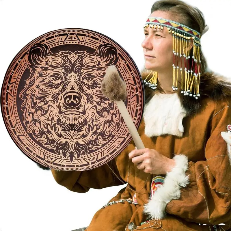 Tambour Chamanique Circulaire au Motif d'Ours sur fond blanc dans les mains d'un homme en tenue amérindienne tenant aussi un pilon