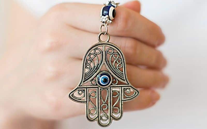 Une main portant un talisman en forme de main de Fatma avec un œil bleu au centre.