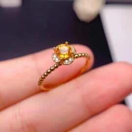 Bague Citrine au Design de Fleur en Argent tenue entre deux doigts