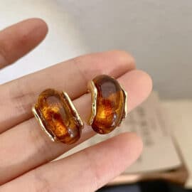 Boucles d’Oreille Ambre Dorées en Alliage de Zinc dans la main d'une personne