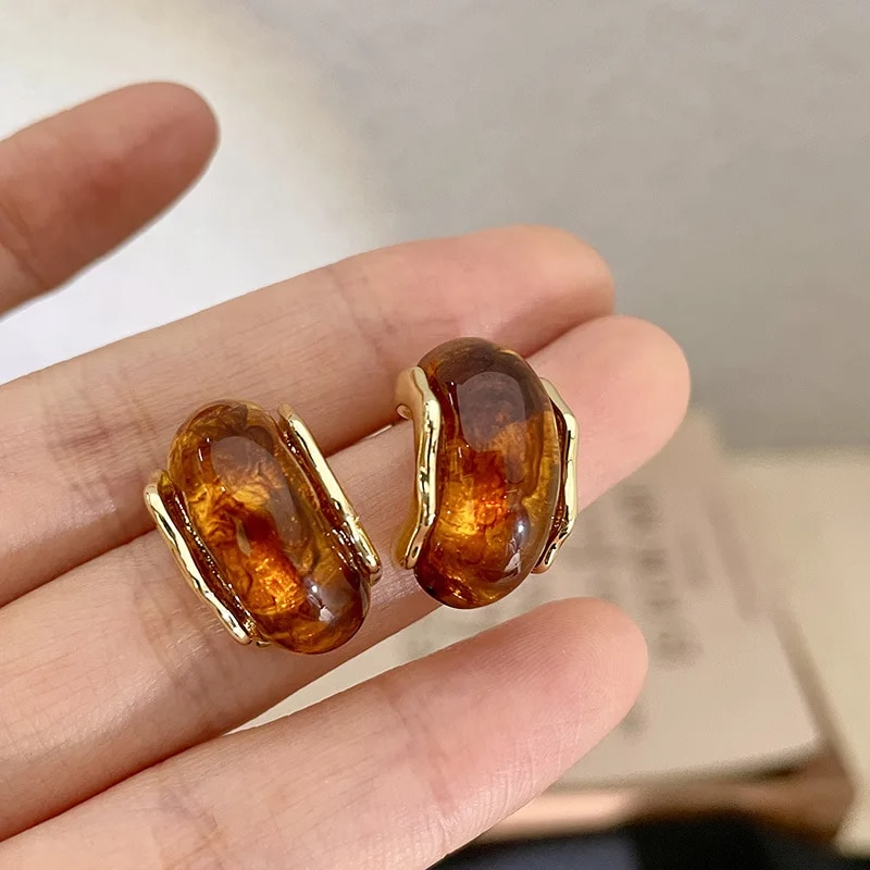 Boucles d’Oreille Ambre Dorées en Alliage de Zinc dans la main d'une personne